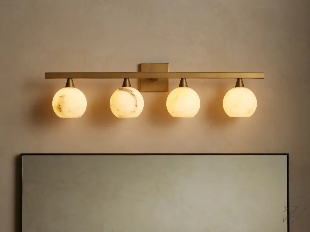 ichandelier Arica 4-light sconce with alabaster globes and brass finish, mounted above a mirror.